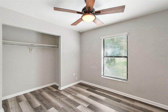 unfurnished bedroom featuring ceiling fan, a closet, and hardwood / wood-style flooring