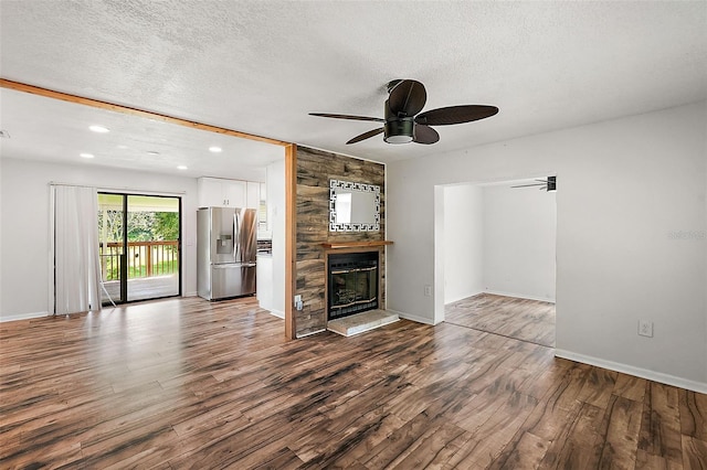 unfurnished living room with a large fireplace, ceiling fan, hardwood / wood-style flooring, and a textured ceiling