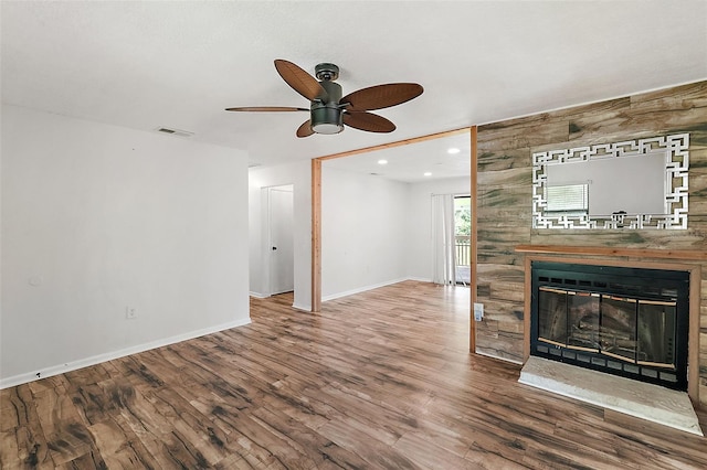 unfurnished living room with hardwood / wood-style floors, ceiling fan, and wooden walls