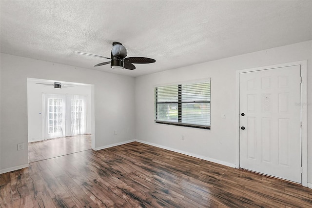 empty room featuring ceiling fan, dark wood-type flooring, and a textured ceiling