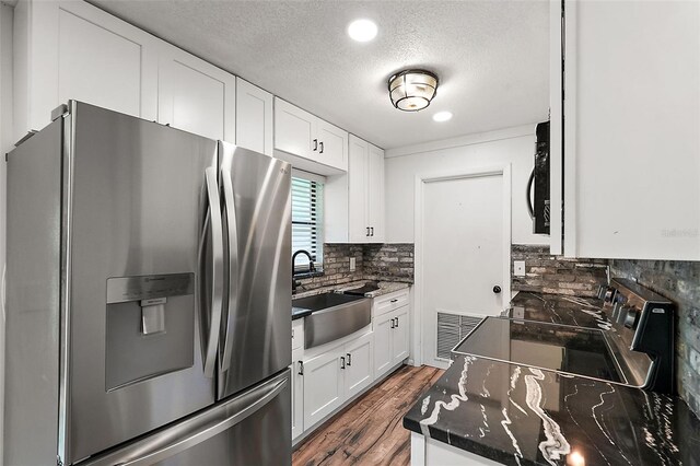 kitchen with decorative backsplash, white cabinetry, dark hardwood / wood-style floors, and appliances with stainless steel finishes