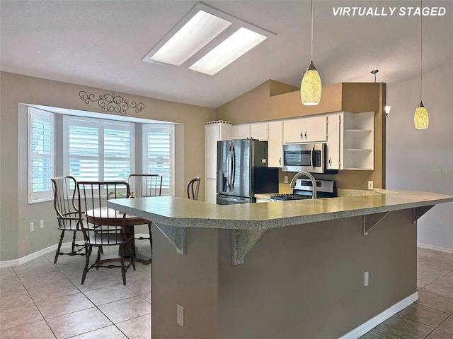 kitchen featuring white cabinetry, a breakfast bar, decorative light fixtures, and appliances with stainless steel finishes