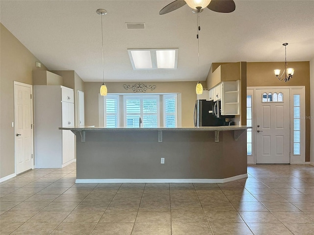 kitchen with stainless steel refrigerator, white cabinetry, pendant lighting, a breakfast bar, and light tile patterned flooring