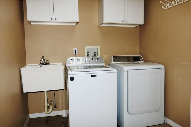 laundry room with dark tile patterned flooring, cabinets, sink, and washing machine and clothes dryer