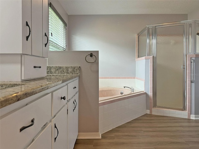 bathroom with hardwood / wood-style floors, vanity, and shower with separate bathtub