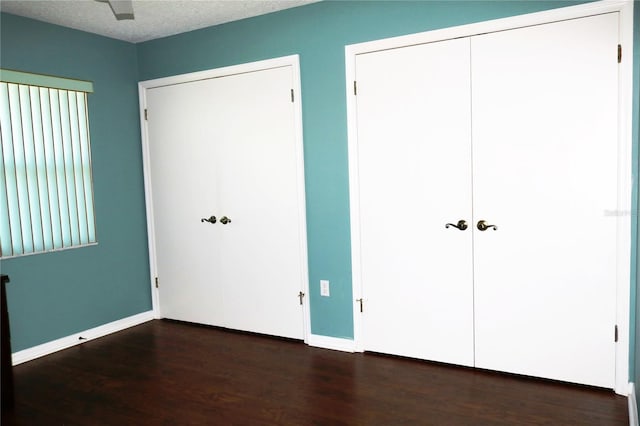 unfurnished bedroom with ceiling fan, dark hardwood / wood-style floors, and a textured ceiling