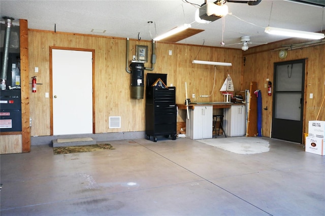 garage featuring a workshop area, wood walls, and a garage door opener