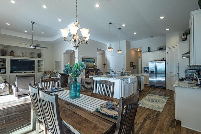 dining room featuring sink, dark wood-type flooring, and ceiling fan with notable chandelier