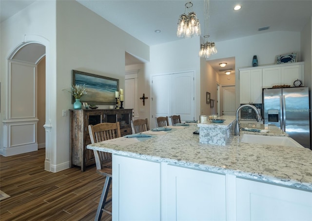 kitchen featuring an island with sink, hanging light fixtures, a breakfast bar, white cabinets, and dark hardwood / wood-style flooring