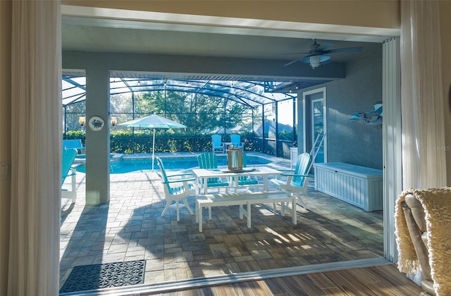 exterior space featuring a patio, ceiling fan, and glass enclosure