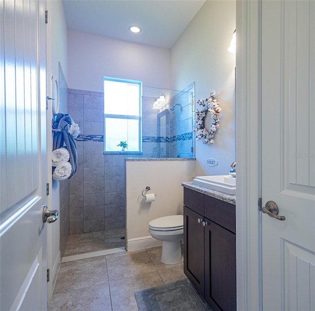 bathroom featuring vanity, tiled shower, toilet, and tile patterned floors