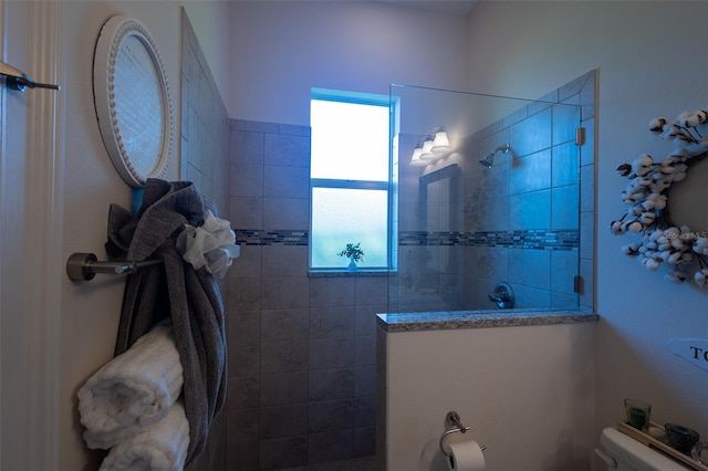 bathroom featuring a tile shower and toilet