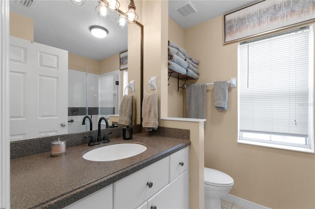 bathroom featuring vanity, toilet, a textured ceiling, and tile patterned floors