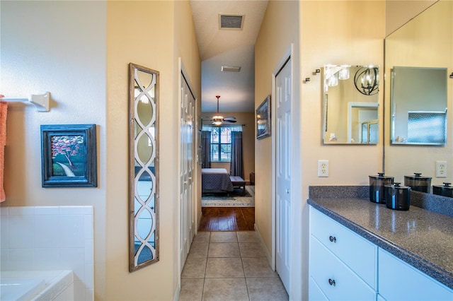 bathroom featuring vaulted ceiling, vanity, a bathing tub, a textured ceiling, and wood-type flooring