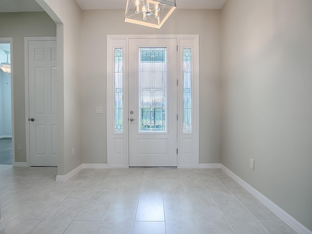 foyer with a chandelier, plenty of natural light, and light tile patterned flooring