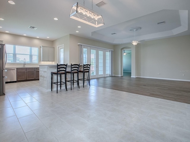 dining area with light hardwood / wood-style floors, a tray ceiling, ceiling fan, and french doors