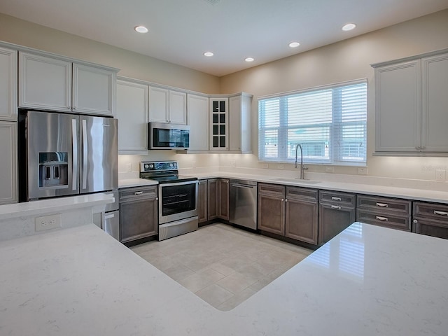 kitchen featuring light stone countertops, stainless steel appliances, and sink