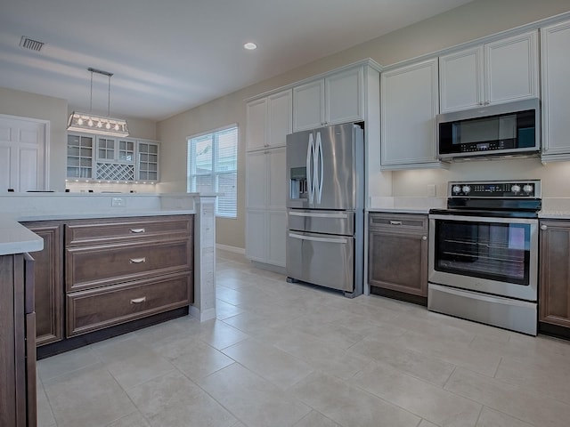 kitchen with pendant lighting, stainless steel appliances, light tile patterned flooring, and dark brown cabinetry