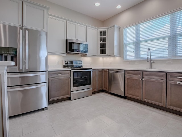 kitchen featuring appliances with stainless steel finishes, white cabinetry, sink, and light tile patterned floors