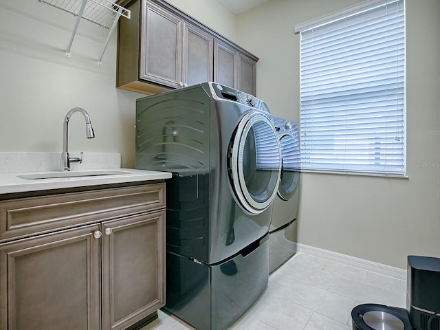 laundry area with separate washer and dryer, sink, light tile patterned floors, and cabinets