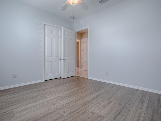 unfurnished bedroom featuring light wood-type flooring, ceiling fan, and a closet