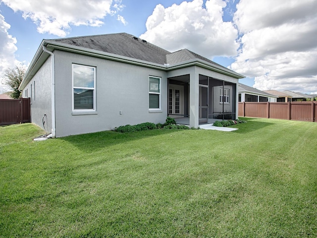 rear view of house with a sunroom and a yard