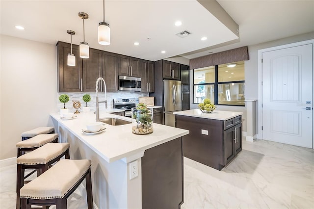 kitchen featuring tasteful backsplash, a breakfast bar area, kitchen peninsula, hanging light fixtures, and stainless steel appliances