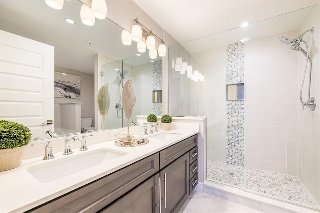 bathroom featuring a tile shower, vanity, and toilet