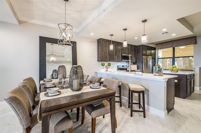 dining space with ornamental molding, an inviting chandelier, and sink