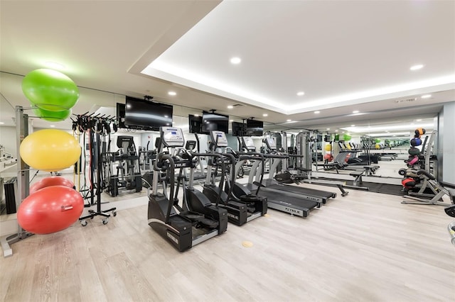 exercise room with light hardwood / wood-style flooring and a raised ceiling