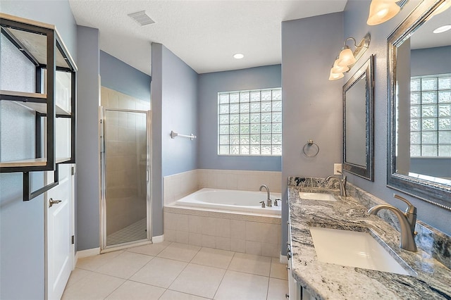 bathroom featuring plus walk in shower, vanity, tile patterned flooring, and a textured ceiling