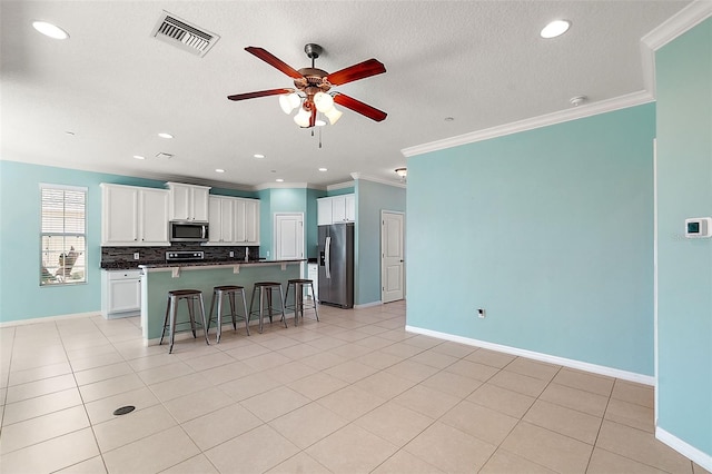 kitchen featuring a center island, crown molding, a kitchen bar, white cabinets, and appliances with stainless steel finishes