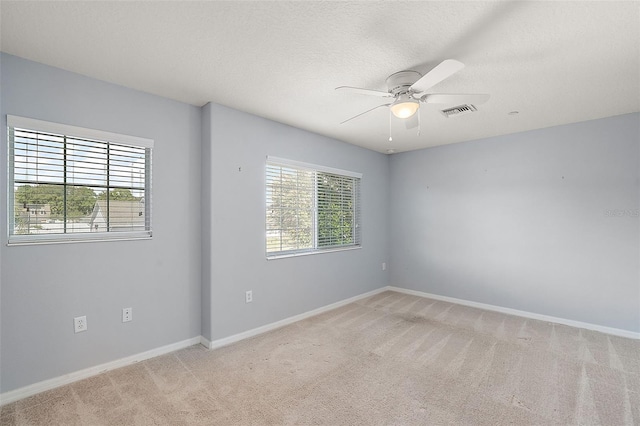 carpeted empty room with plenty of natural light, ceiling fan, and a textured ceiling