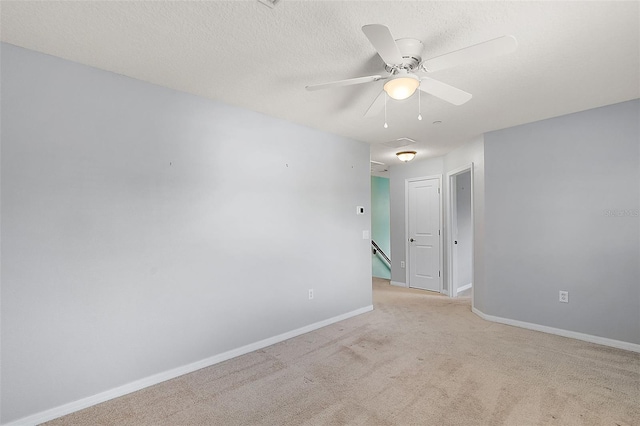 unfurnished room featuring light carpet, a textured ceiling, and ceiling fan