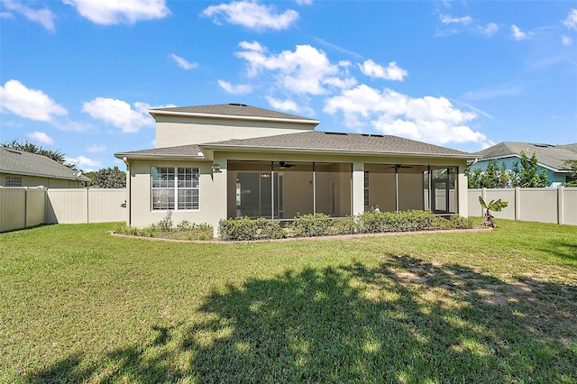 rear view of property with a sunroom, ceiling fan, and a yard