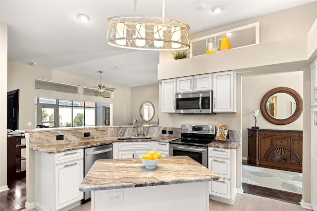 kitchen featuring stainless steel appliances, a kitchen island, hanging light fixtures, and sink