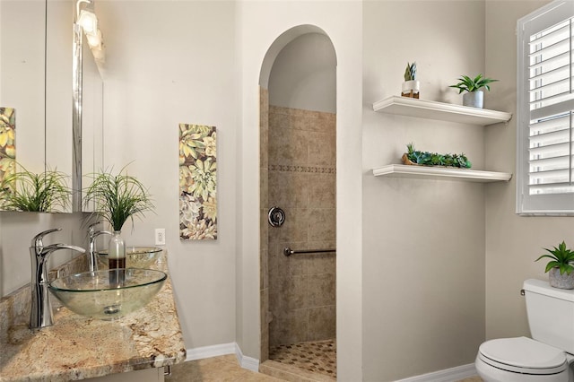 bathroom with tile patterned floors, toilet, vanity, and a tile shower