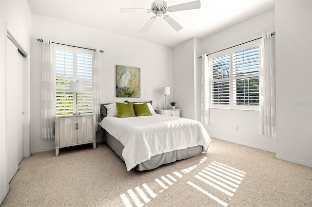 bedroom with multiple windows, light carpet, ceiling fan, and a closet