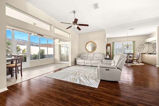 living room with ceiling fan, plenty of natural light, dark hardwood / wood-style floors, and a textured ceiling