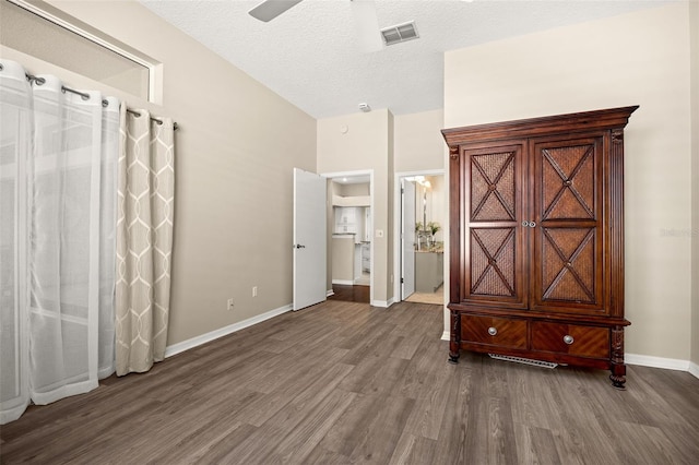 unfurnished bedroom with ceiling fan, dark hardwood / wood-style floors, ensuite bath, and a textured ceiling