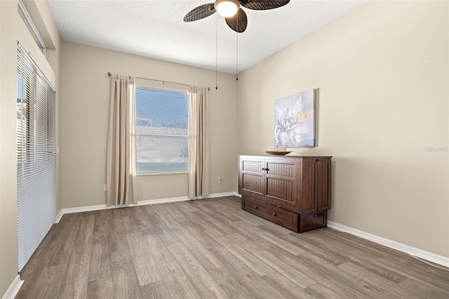 unfurnished bedroom with ceiling fan, a textured ceiling, and light wood-type flooring