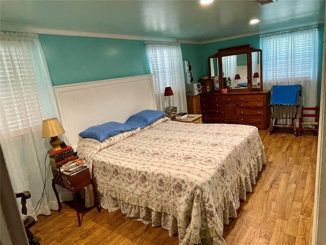 bedroom with ornamental molding and light wood-type flooring