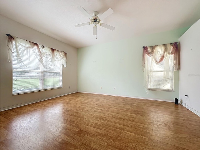 empty room featuring wood-type flooring, ceiling fan, and plenty of natural light