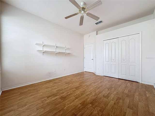 unfurnished bedroom with wood-type flooring, ceiling fan, and a closet