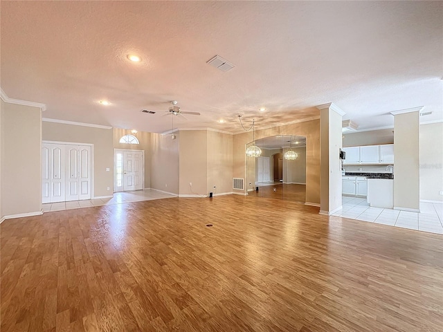 unfurnished living room featuring ceiling fan with notable chandelier, a textured ceiling, light hardwood / wood-style flooring, and crown molding