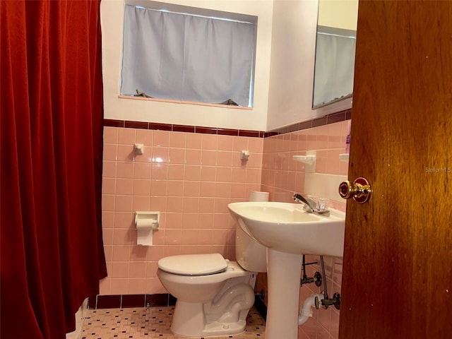 bathroom featuring tile walls, tile patterned floors, and toilet