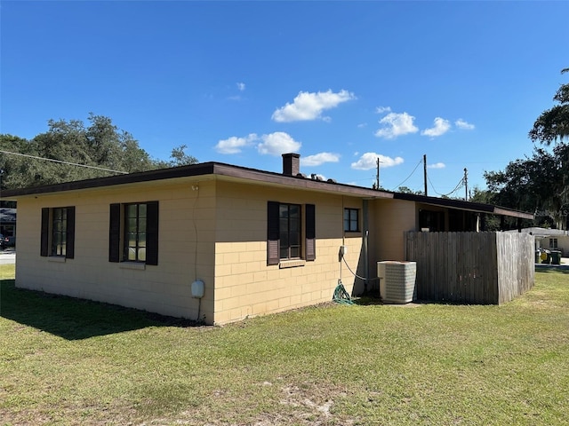 rear view of property featuring a yard and central air condition unit