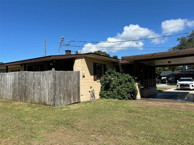 view of property exterior with a lawn and a carport