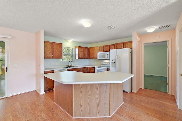 kitchen featuring light hardwood / wood-style flooring, sink, white appliances, and a kitchen island