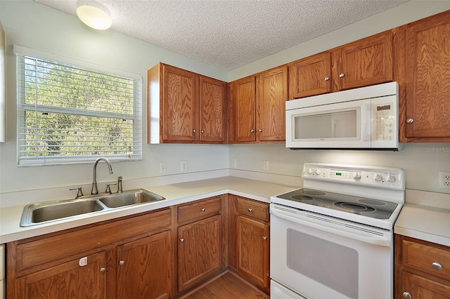 kitchen featuring white appliances, a textured ceiling, and sink